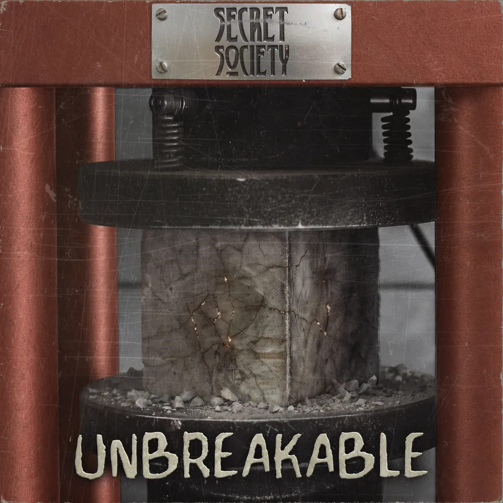 Unbreakable cover: a stone block in a rust-red hydraulic press